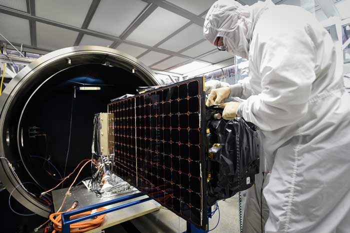 Person in clean suit inspects large device