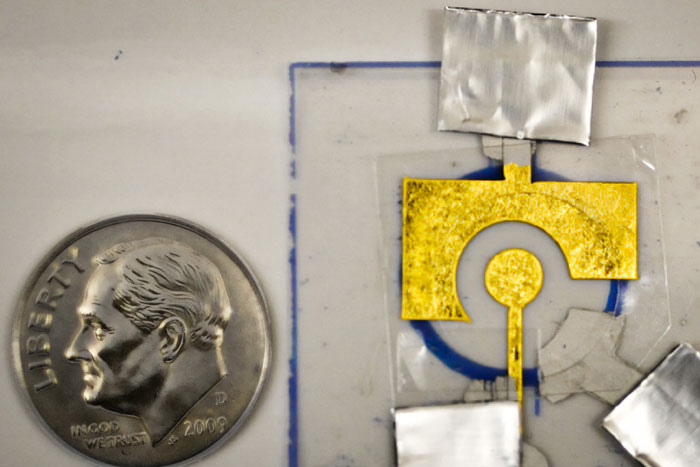 small gold-covered electrode next to a dime