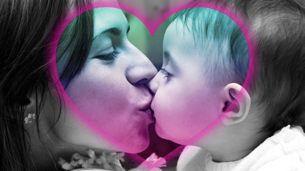 Edited photo showing a mother kissing her baby, with their faces inside a colorful heart