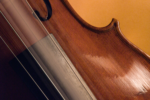 Closeup of a vibrating violin string on an orange background.