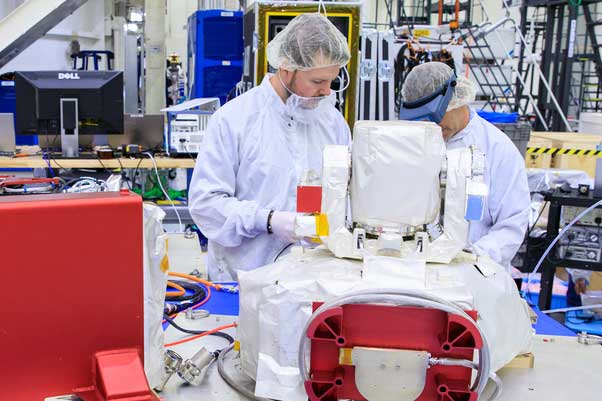 Lincoln Laboratory staff members Justin Dunbeck (left) and Steven Constantine unpack and examine the Optical Communications System moon sample.