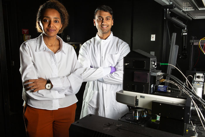 Loza Tadesse and Aditya Garg stand next to the Raman microscope.