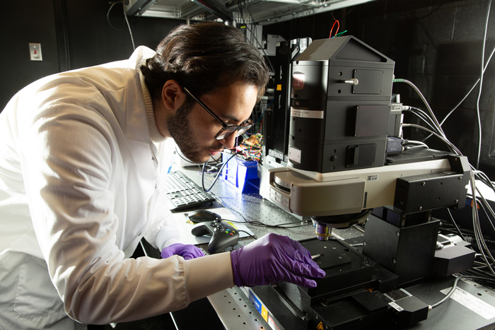 Researcher looks at tiny device with microscope